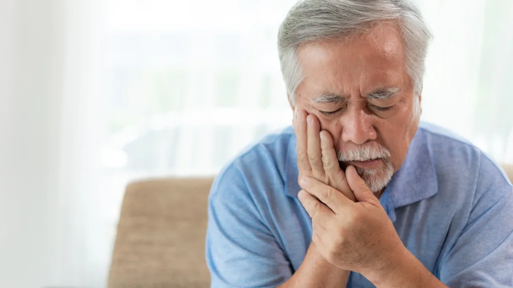 Hombre adulto mayor con dolor de muela buscando atención de urgencias odontológicas en Bogotá en la Clínica Protección Oral para aliviar su malestar.